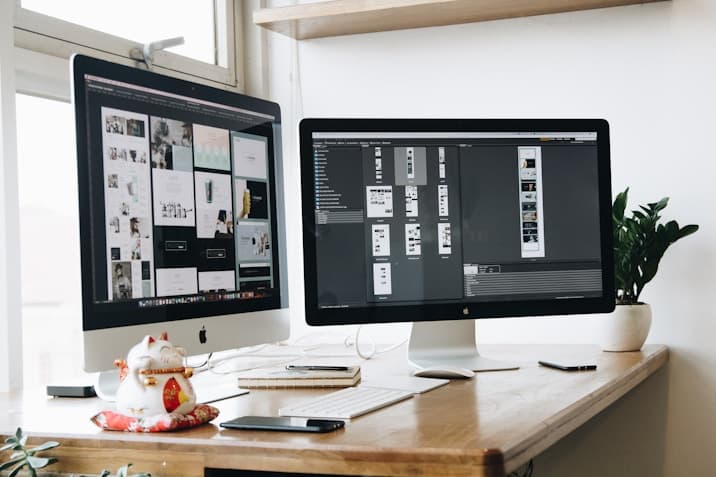 Two monitors showing design work on a desk